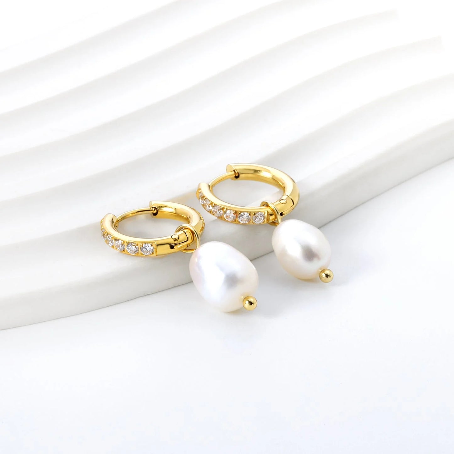 Deze prachtige oorbellen hebben een cirkelvormig ontwerp van 2,5 x 14 mm met 6 sprankelende witte zirconia, perfect aangevuld door een glanzende ovale witte parel van 8,3 x 13 mm. Verfraaid met een luxueuze goudkleur, zijn deze oorbellen de belichaming van elegantie en verfijning. Geef elke look een boost met deze tijdloze en moeiteloos mooie oorbellen