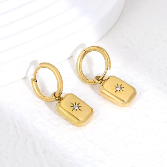 Elegante oorringen met een achtpuntige ster, versierd met sprankelende witte strass-steentjes. De rechthoekige sterhanger meet 9,3 × 12,4 mm en hangt aan een binnenring van 2,0 × 10 mm, wat zorgt voor een evenwichtig en opvallend silhouet. Deze oorbellen zijn gemaakt van hypoallergeen roestvrij staal met een 18K gouden plating, waardoor ze zacht zijn voor de gevoelige huid en bestand zijn tegen verkleuring. Met een gewicht van slechts 5 gram per paar zijn ze licht en comfortabel om de hele dag te dragen. Pe